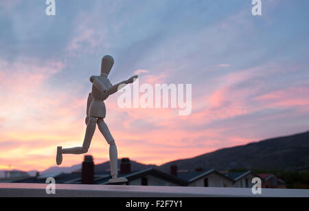 Wooden figure mannequin running at sunset Stock Photo