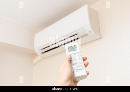 Hand with remote control directed on the conditioner. Stock Photo