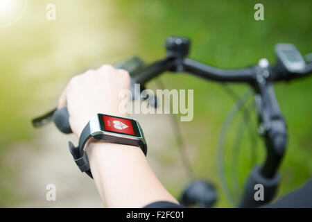 Woman riding a bike with a smartwatch heart rate monitor. Smart watch concept. Stock Photo
