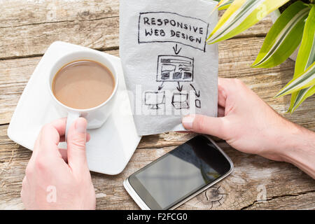 Web designer holding a blueprint of a new mobile application. Responsive web design concept. Stock Photo