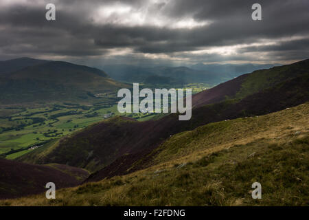 Moody skies from Blencathra in the Lake District with the sun lighting up the heather on the slopes, UK Stock Photo