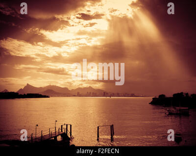 Sun rays streaming through clouds and reflecting on the water in Rio de Janeiro, Brazil. Stock Photo