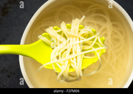 Spoon spaghetti pasta pulls out of the pan with water top view Stock Photo