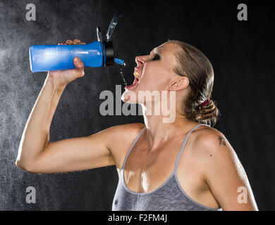 Thirsty Athletic Woman Drinking Water in a Bottle Stock Photo