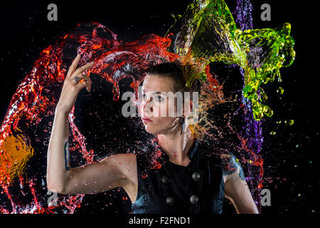 Modern Woman Being Splashed with Colorful Water Stock Photo