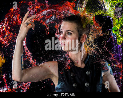 Modern Woman Being Splashed with Colorful Water Stock Photo