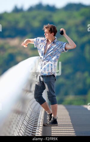 Young Man Standing on the Bridge Throwing Down Something Stock Photo