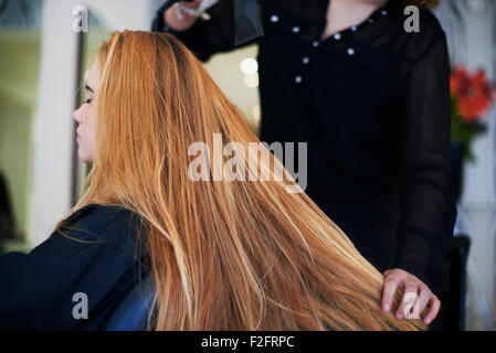Hairdresser drying customer’s long hair in salon Stock Photo