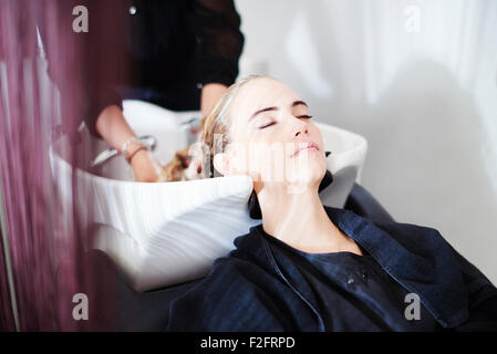 Customer with eyes closed getting hair washed in salon Stock Photo
