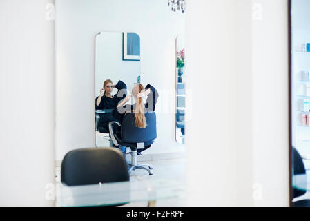 Customer with long hair looking into mirror in hair salon Stock Photo