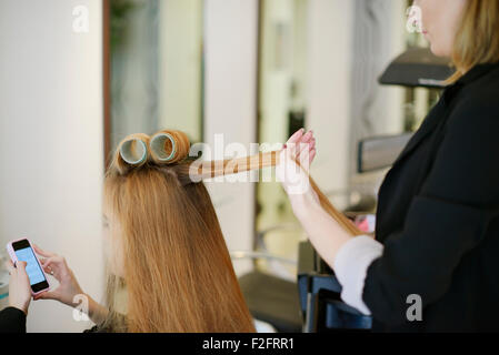 Hairdresser rolling customer’s hair in curlers in salon