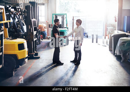 Mechanic and customer handshaking in auto repair shop Stock Photo