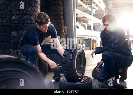 Mechanics fixing tire in auto repair shop Stock Photo