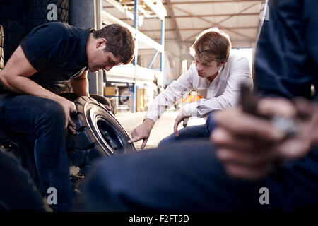 Mechanic and customer examining tire in auto repair shop Stock Photo
