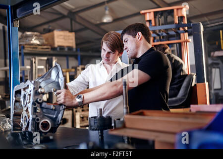 Mechanic and customer examining part in auto repair shop Stock Photo
