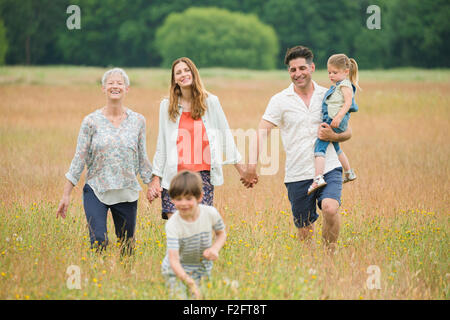 Multi-generation family holding hands and walking in rural field Stock Photo
