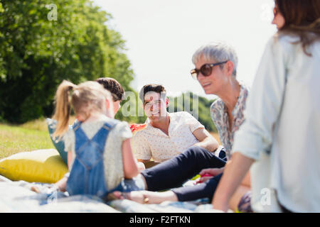 Multi-generation family relaxing on blanket in sunny field Stock Photo
