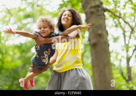 Playful mother flying son under tree Stock Photo