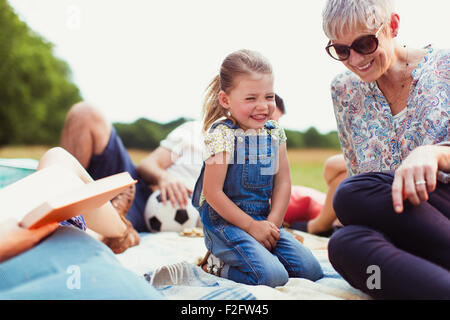 Grandmother and granddaughter laughing on blanket Stock Photo