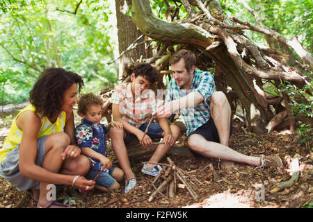 Family making small campfire in woods with sticks Stock Photo