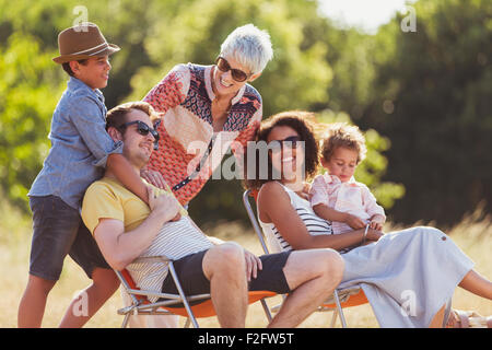 Multi-generation family relaxing in sunny field Stock Photo