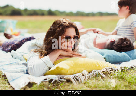 Family relaxing on blanket in sunny field Stock Photo