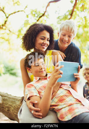 Multi-generation family using digital tablet outdoors Stock Photo