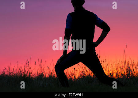 Billingham, UK. 18th September, 2015. Weather: A brief glimpse of glorious colours at sunrise for this jogger, stretching in Cowpen Bewley Woodland Park, before the sun disappeared behind low cloud. Credit:  Alan Dawson News/Alamy Live News Stock Photo