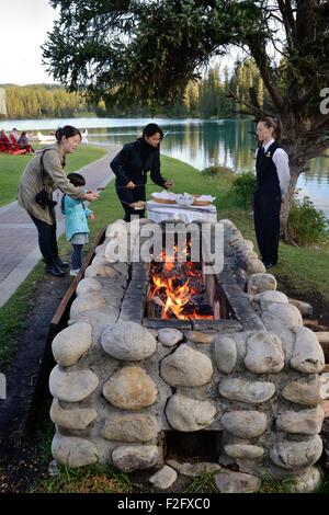 Toasting marshmallows over an open fire at the Jasper Park Lodge, Jasper, Alberta, Canada. Stock Photo