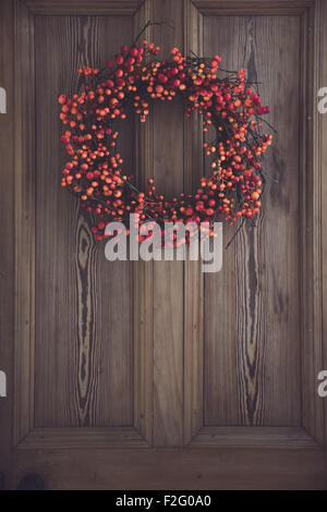 Fall berry wreath hanging on a wooden door Stock Photo