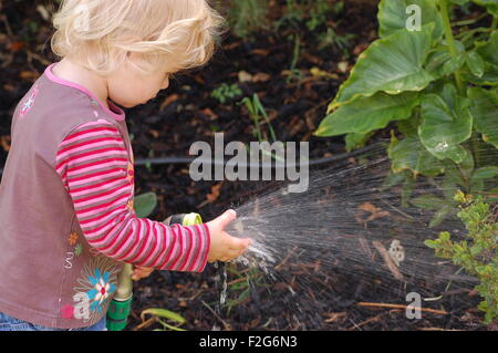 A little girl playing with water coming out of a hose Stock Photo