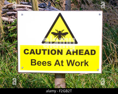 Warning Sign placed near bee hives 'Caution Ahead Bees At Work' Stock Photo