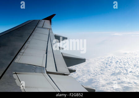 cloudy sky and airplane wing as seen through window of an aircraft. Stock Photo