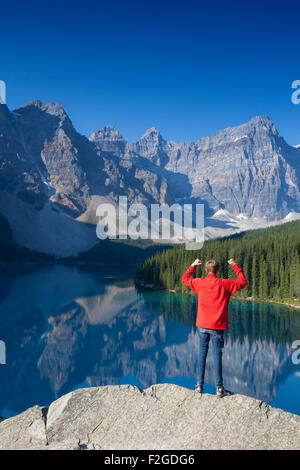 Tourist with open arms on look-out point looking over Moraine Lake in the Valley of the Ten Peaks, Banff NP Alberta, Canada Stock Photo