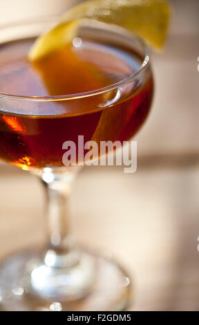 amber cocktail in coupe glass with lemon twist Stock Photo