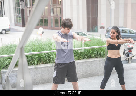 Couple of young handsome caucasian sportive man and woman doing squat, one looking downward, the other looking her friend - sportive, healthy, fitness concept Stock Photo