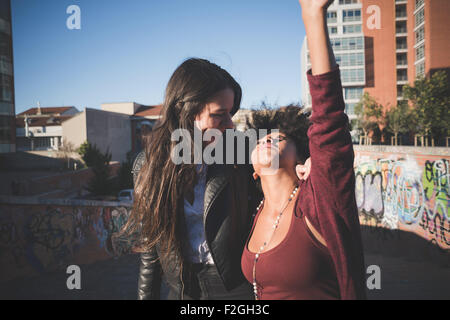 Half length of two multiethnic beautiful young woman black and caucasian having fun in town, hugging and laughing - carefreeness, freshness, youth concept Stock Photo