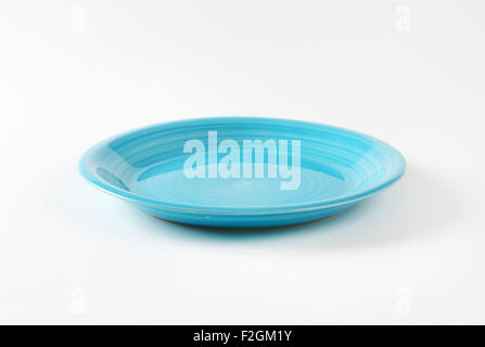 Coup shaped ceramic plate with a blue color glaze Stock Photo