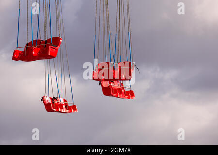 Red Carousel seats on cloudy sky Stock Photo