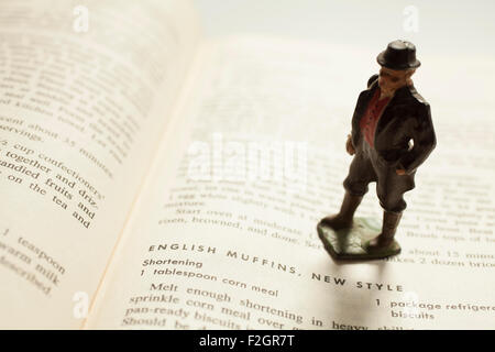 An antique lead toy English gentleman poses on an old cookbook. Stock Photo
