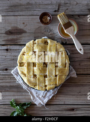 A lattice-top caramel apple pie before it goes to the oven displayed on a farm table. Stock Photo