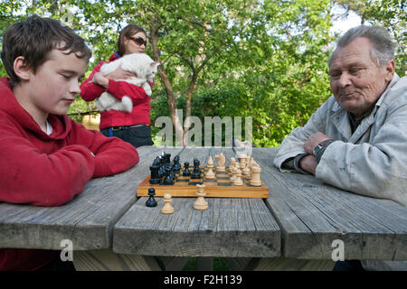 Grandfather and boy playing game of chess in the garden Stock Photo