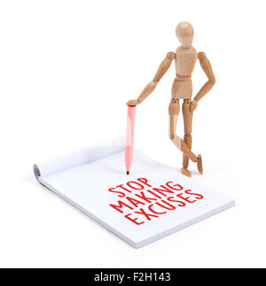 Wooden mannequin writing in a scrapbook - Stop making excuses Stock Photo