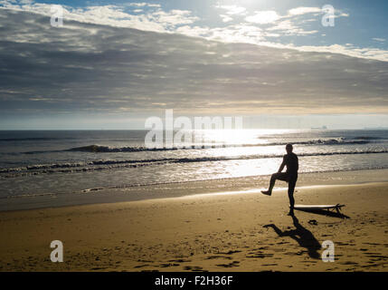 Surfer stretching on Seaton Carew beach at sunrise. north east England. United Kingdom Stock Photo