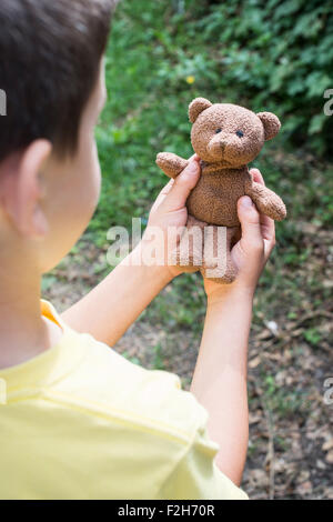 Child hold teddy in a garden. Stock Photo