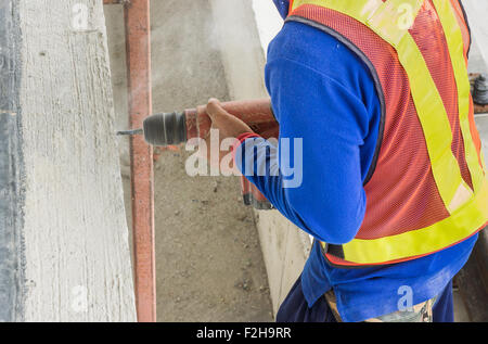 Worker drilling the concrete wall at a construction site Stock Photo