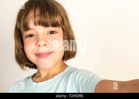 Happy little girl take a selfie with a smart phone at home isolated on white background Stock Photo