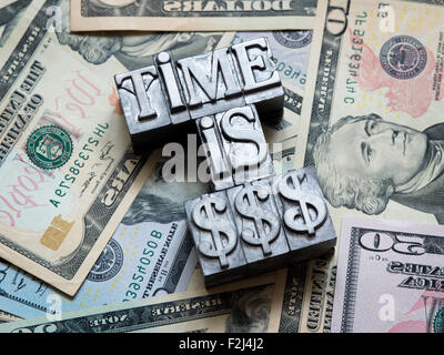 time is money concept made from metallic letterpress type on heap of US dollars Stock Photo