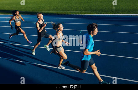 Group of multiracial athletes practicing running on racetrack. Male and female athletes during running session at athletics stad Stock Photo