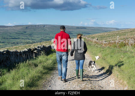 Couple holding hands walking along Roman road heading towards Bainbridge from Burtersett in the Yorkshire Dales National park, U Stock Photo